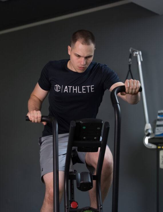 Trener wykonuje ćwiczenia na rowerze powietrznym w prywatnym studio treningowym