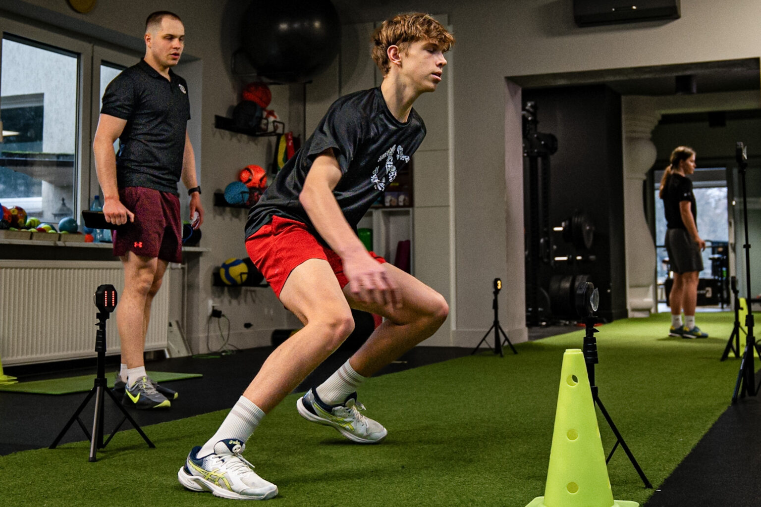 Młody sportowiec wykonujący trening zwinności pod okiem trenera Dawida Dzikiewicza w profesjonalnym studiu treningowym w Poznaniu.